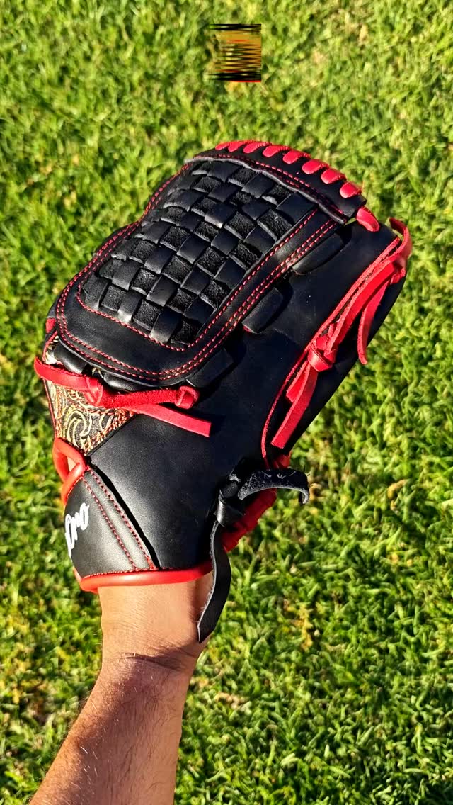 Stealth mode activated. 🥷🔴 This custom masterpiece brings the ultimate heat with a sleek matte black shell, vibrant red lacing, and precision red stitching. Look closer and you'll spot that intricate gold-and-black paisley accent on the wrist cutout, perfectly complementing the classic basket web.Absolute luxury built for the diamond.Rate this clean execution from 1-10! 👇#deorosports #customgloves #baseball #softball #fyp #pitchersglove #baseballlife #glovelove #glovegains